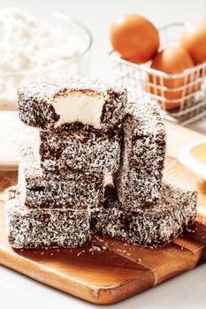 Group of Lamingtons on a timber metal baking tray with food ingredients in the background