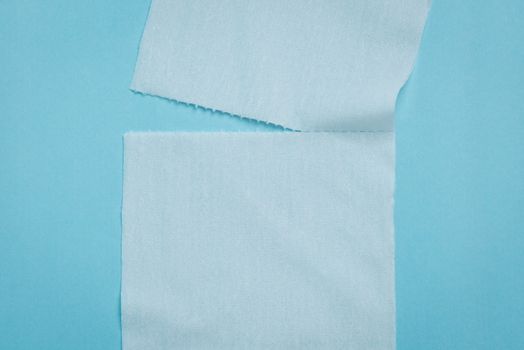 Two pieces of toilet paper being ripped apart on a blue background.