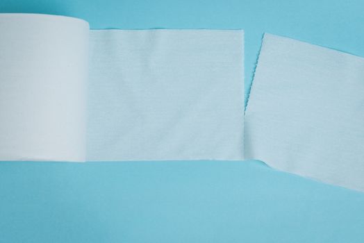 Two pieces of toilet paper being ripped apart on a blue background.