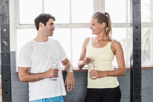 Fit couple holding water bottles in crossfit gym