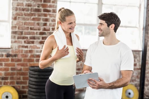 Woman discussing her performance on clipboard with trainer in crossfit gym