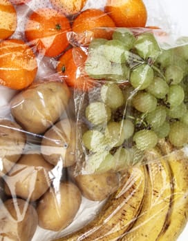 tangerines, grapes, bananas and potatoes stored in cellophane bags for food