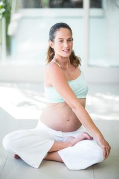 Happy pregnant woman practicing yoga on floor at home