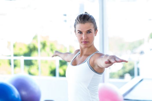 Serious woman with arms outstretched in fitness studio