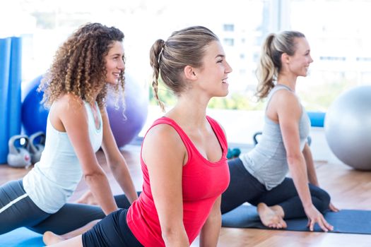 Cheerful women doing pigeon pose in fitness studio