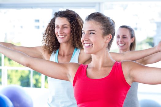 Cheerful women with arms outstretched in fitness studio