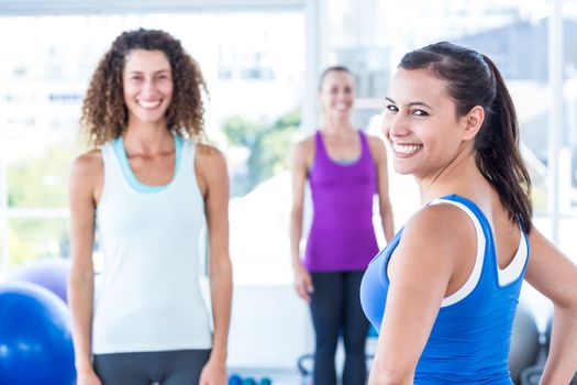 Portrait of cheerful woman with friends at fitness center while standing