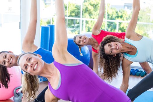Cropped image of cheerful women doing side stretch in fitness studio