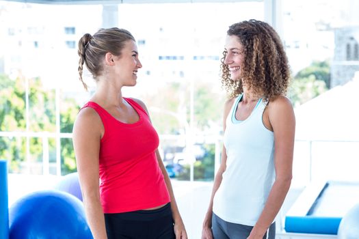 Happy women looking at each other and smiling in fitness studio