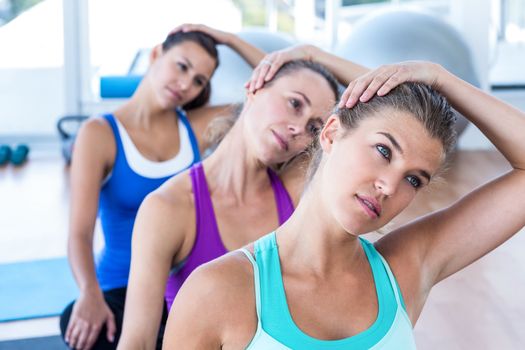 Beautiful woman in fitness studio doing head exercise while sitting
