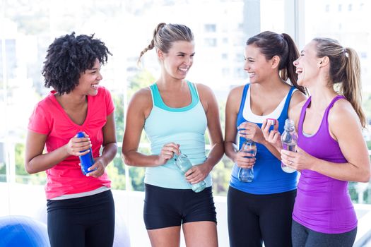 Cheerful women holding water bottle in fitness studio