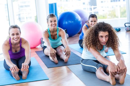 Woman sitting in forward bend pose in fitness studio