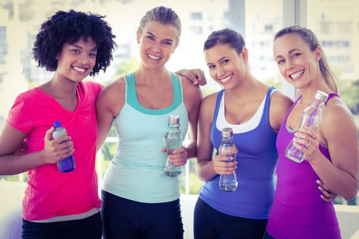 Portrait of beautiful women holding water bottle in fitness studio