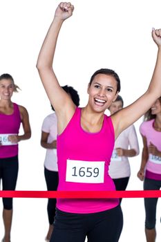 Smiling winner athlete crossing finish line with arms raised against white background
