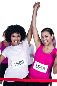 Portrait of cheerful winner athletes crossing finish line with arms raised against white background