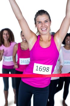Portrait of smiling winner athlete crossing finish line with arms raised against white background