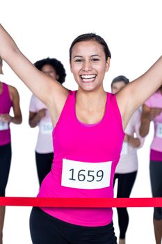Portrait of cheerful winner athlete crossing finish line with arms raised against white background