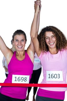 Portrait of happy winner athletes crossing finish line with arms raised against white background