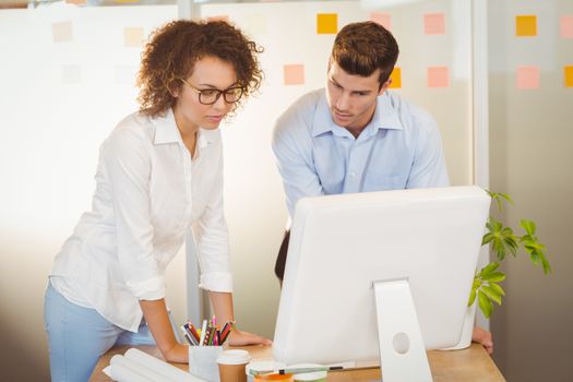 Business people standing by table using computer in office