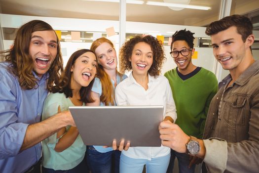 Portrait of happy business people with laptop in meting room at creative office