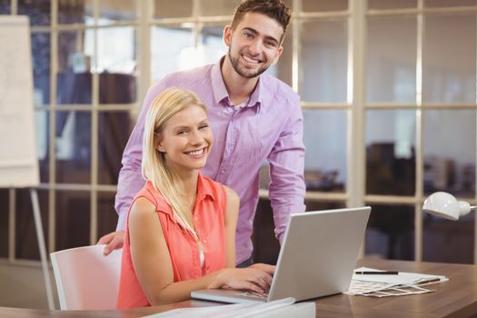 Portrait of happy business people with laptop in creative office