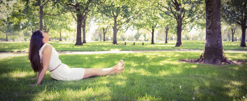 Panoramic view of park while young woman relaxing on grassland