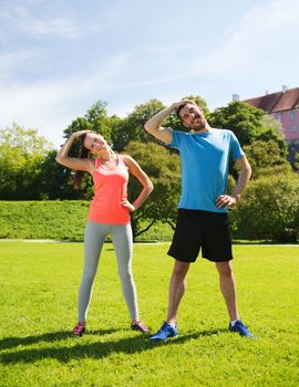 fitness, sport, training and lifestyle concept - smiling couple stretching outdoors