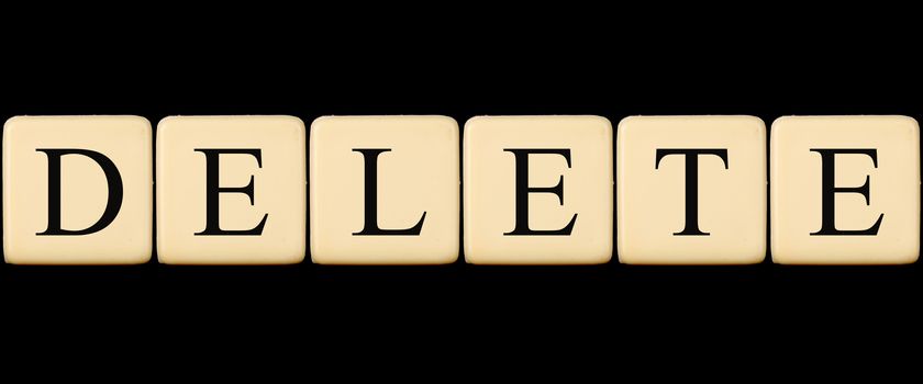 A delete word made from scrabble tiles, on black studio background.