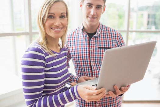 Portrait of college students using laptop while standing by laptop