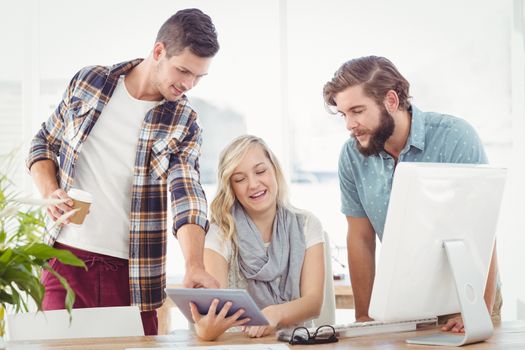 Business professionals using digital tablet while sitting at desk in office