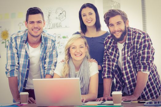 Portrait of smiling colleagues working on laptop at desk in office