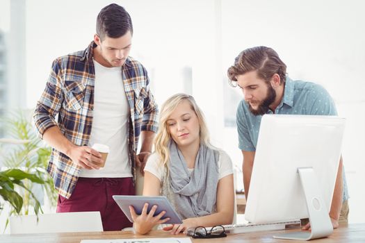 Business people using digital tablet while sitting at desk in office