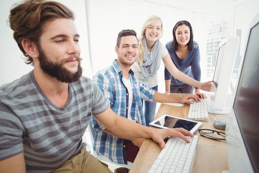 Cheerful business team at computer desk in office