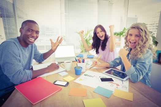 Portrait of smiling business people gesturing while sitting at desk in creative office