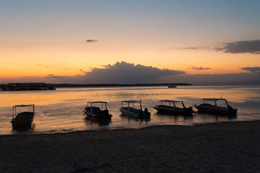 sunset on Bali sea, Nusa Penida Island, Toyapakeh, Indonesia - boat with silhouette of Bali at evening with dramatic sky