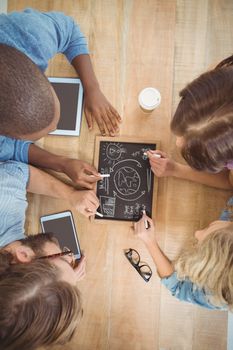 Close-up of people writing business terms on slate at table 