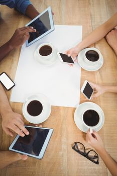 Overhead view of people using smartphones and digital tablet at desk in office