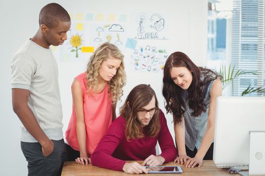 Man using digital tablet with business team at desk in office