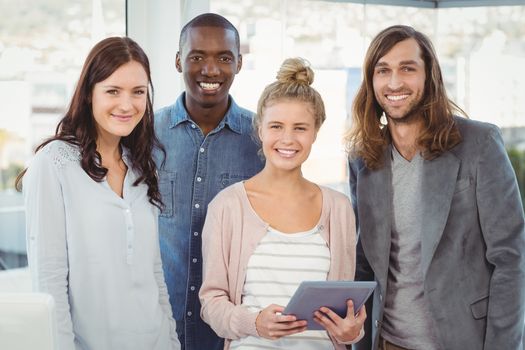 Portrait of smiling business team with woman holding digital tablet at office