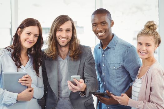 Portrait of smiling business team using technology while standing at office