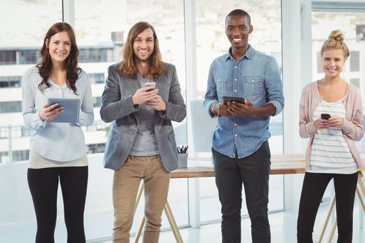 Portrait of cheerful business team using technology while standing at office