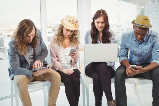 Business people using technology while sitting on chair in creative office