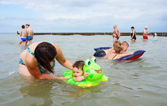 SIANOZETY, POLAND - JULY 21, 2015: Adults and children playing in the water at a beach