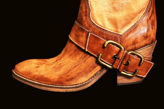 Female boot of the cowboy on a black background