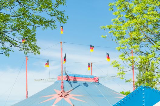 Beautiful colorful circus tent with flags in front of a bright blue sky.
