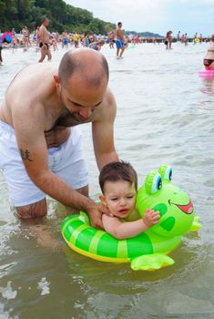 SIANOZETY, POLAND - JULY 21, 2015: Man playing with child in the water at a beach 