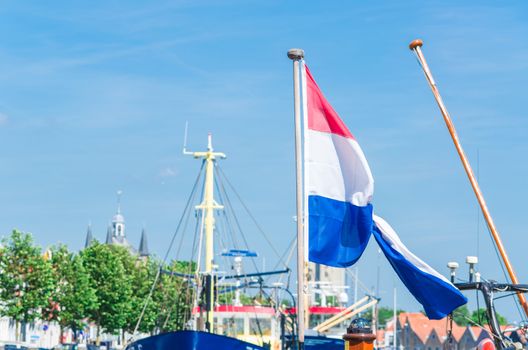 Looking in a dutch Marina, Mast with flag of the Netherlands against blue sky.