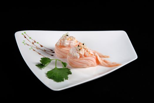 portion of sushi with vegetables on white plate, black background