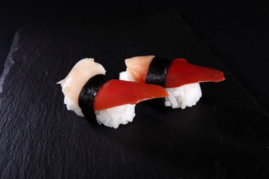 mixed sushi on white plate, black background