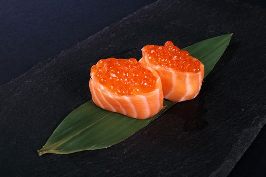 rolls with fish eggs on leaf green, black background